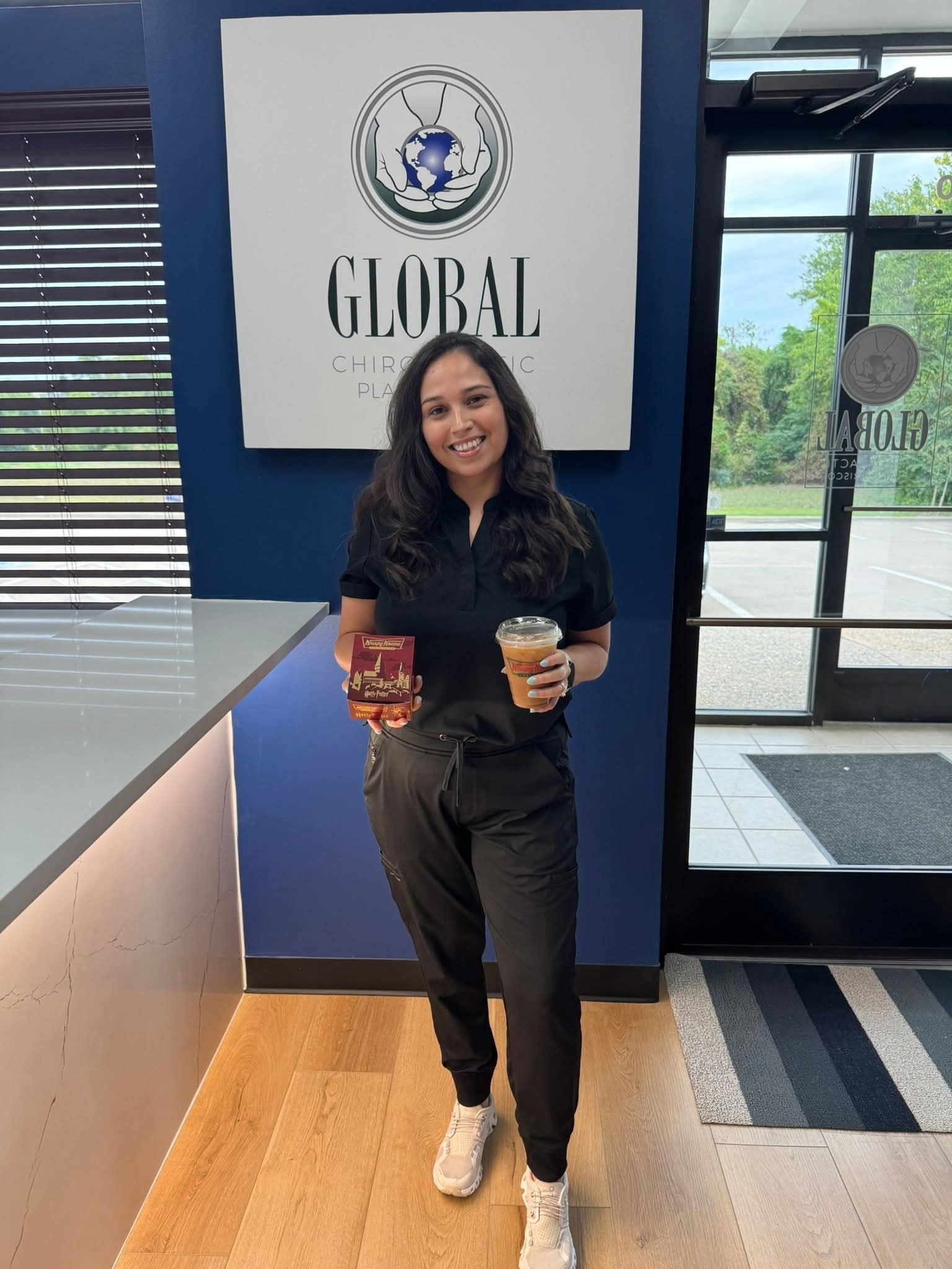 Office Manager at Global Chiropractic Plano Frisco holding coffee in the clinic lobby